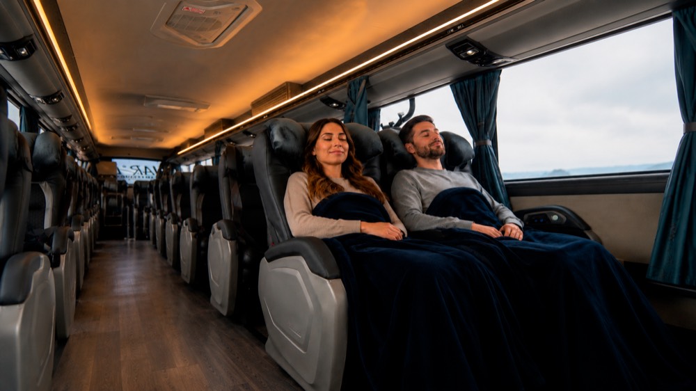 Dos pasajeros descansando con frazadas en un bus climatizado de Nar Bus