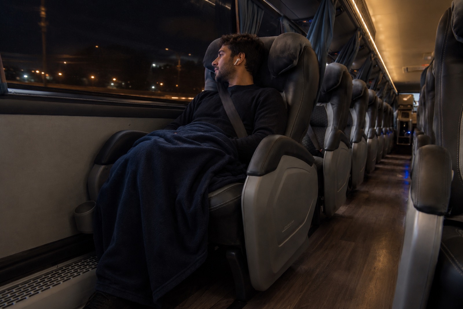 Pasajero descansando de noche en un asiento Salón Cama de Nar Bus, cubierto con una frazada